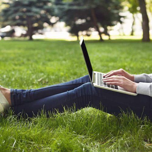 young pensive woman using laptop in park PL35JWE 1