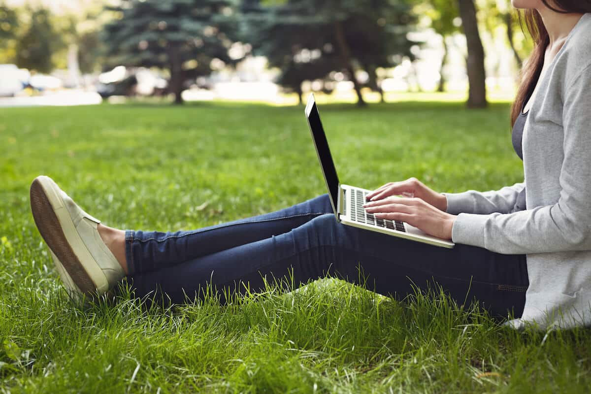 young pensive woman using laptop in park PL35JWE 1